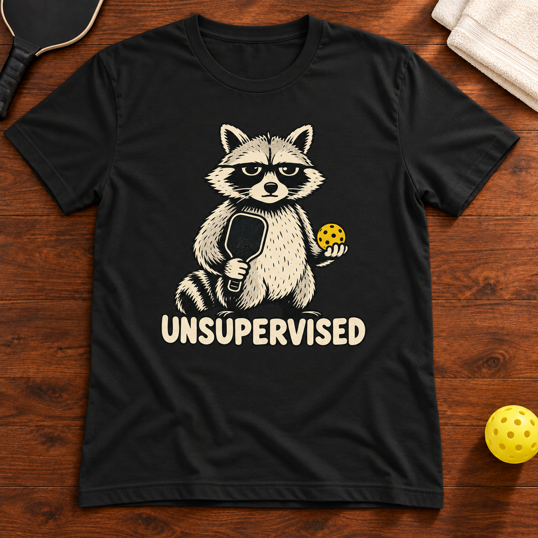 Unsupervised Pickleball Raccoon T-Shirt, vintage-black, warm wood flat lay