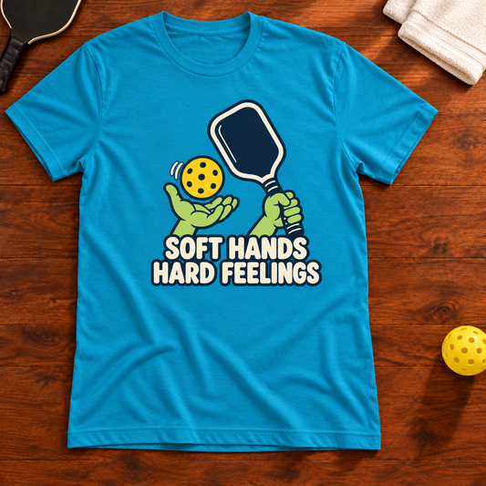 Soft Hands, Hard Feelings Pickleball T-Shirt in aqua, flat lay with corrected paddle artwork